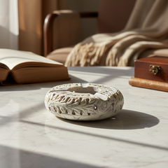 Luxury Hand-Carved Soapstone Ash Tray on a marble surface with an open book, Cigar and wooden box in the background.