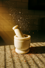 Luxury white marble mortar and pestle with warm ambient lighting with grinding action on a textured surface
