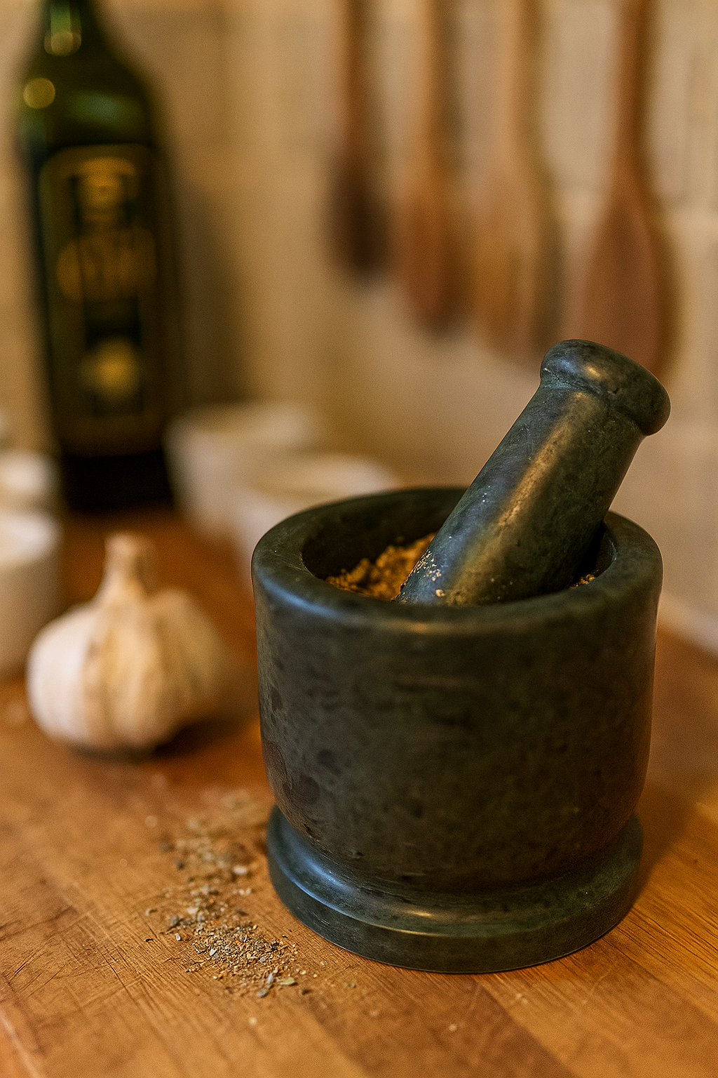 Green marble mortar and pestle with spices on wooden table