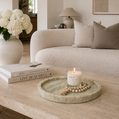 Natural stone marble tray styled in a minimalist living room with candle and decorative accessories.