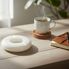 White marble ash tray on a wooden table with a cup of coffee and notebook.