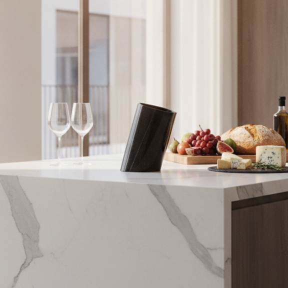 Black marble wine chiller on a contemporary kitchen island with wine glasses and gourmet snacks.